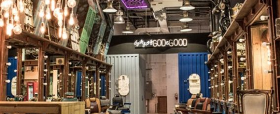 Interior of a vintage-themed barbershop with multiple barber chairs, wooden floors, and eclectic lighting fixtures.